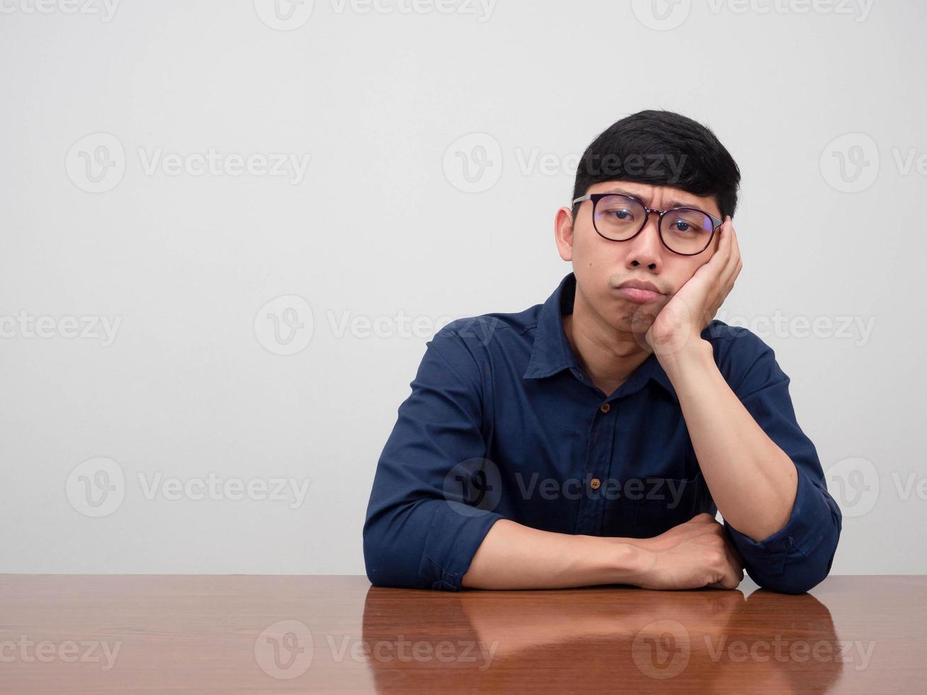 asiatischer geschäftsmann, der eine brille trägt, sitzt am tisch und fühlt sich gelangweilt foto