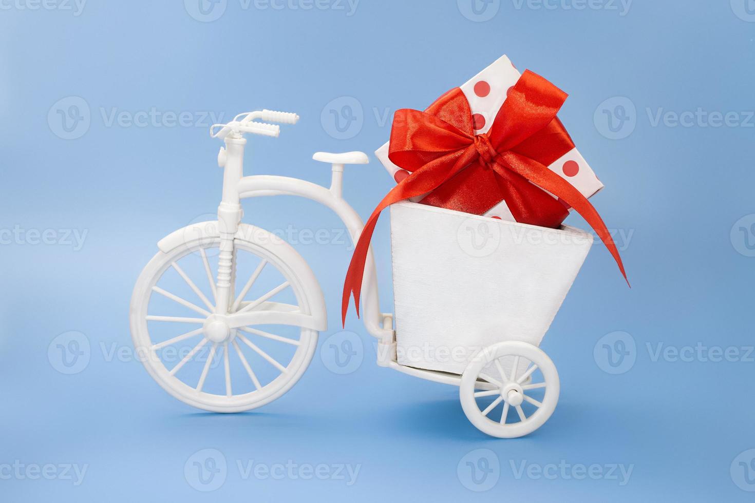 Fahrrad mit Blumenkasten mit weißem Kasten mit Tupfen, Schleife auf blauem Hintergrund. feiertag, valentinstag, internationaler frauen- und muttertag, 8. märz, geburtstag. Platz kopieren foto