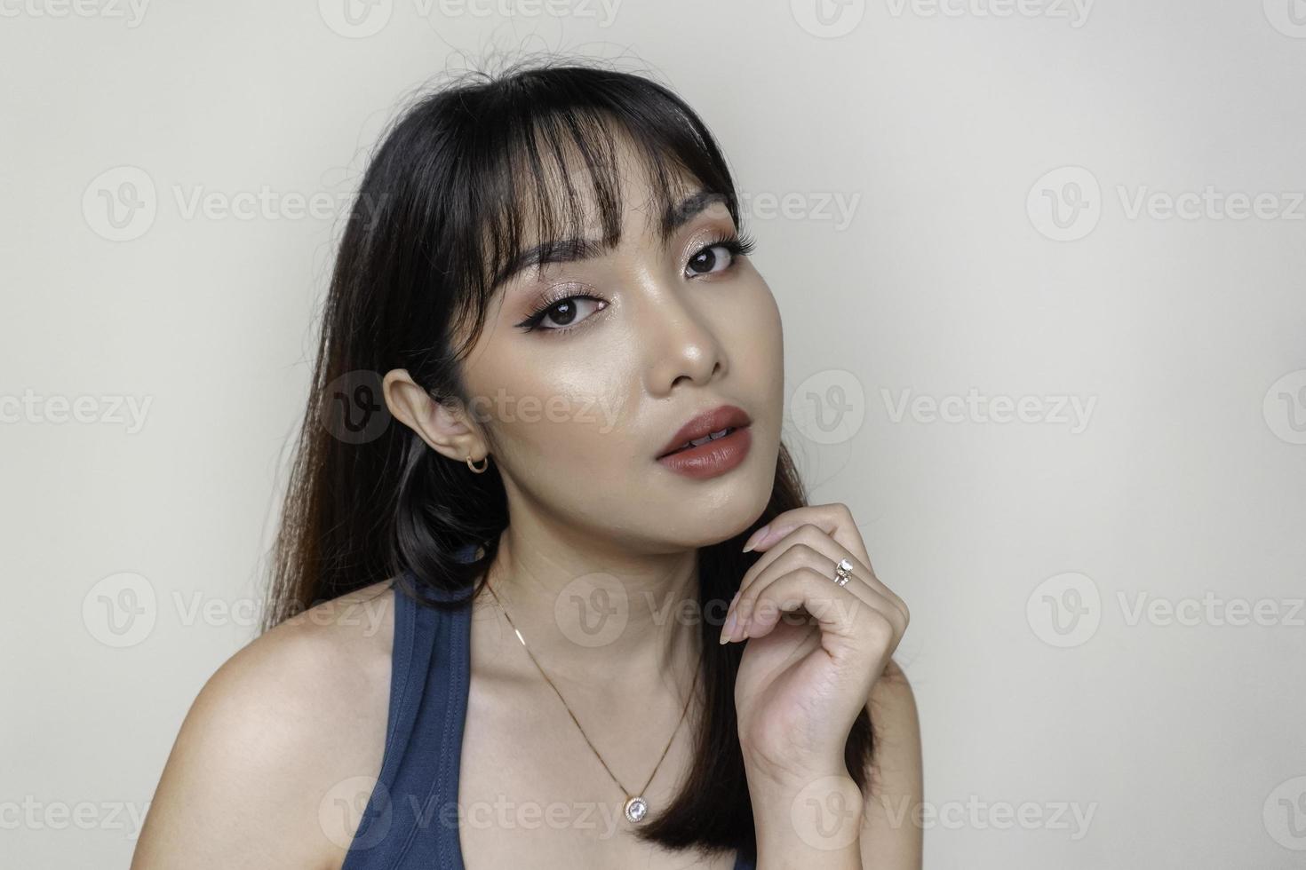ein fröhliches gesicht der schönheit des asiatischen jungen modells, das aquamarines grünes oberteil trägt. make-up hautpflege schönheit gesichtsbehandlung, spa, weibliches gesundheitskonzept. foto