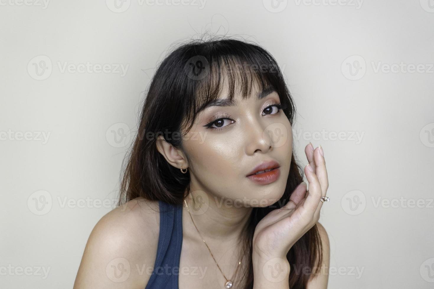 ein fröhliches gesicht der schönheit des asiatischen jungen modells, das aquamarines grünes oberteil trägt. make-up hautpflege schönheit gesichtsbehandlung, spa, weibliches gesundheitskonzept. foto