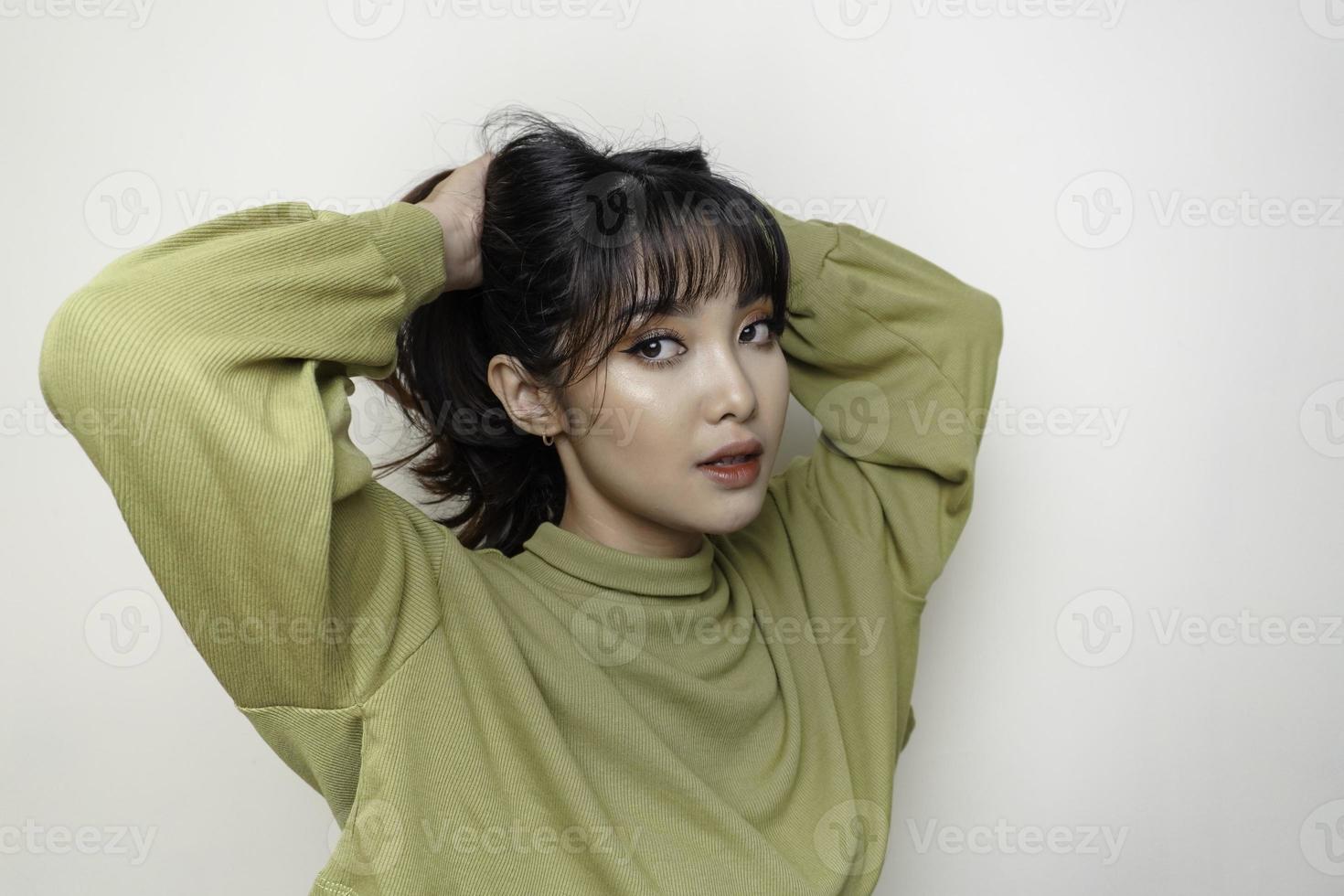 ein fröhliches gesicht der schönheit des asiatischen jungen modells, das grünes oberteil trägt. hautpflege schönheit gesichtsbehandlung, spa, weibliches gesundheitskonzept. foto