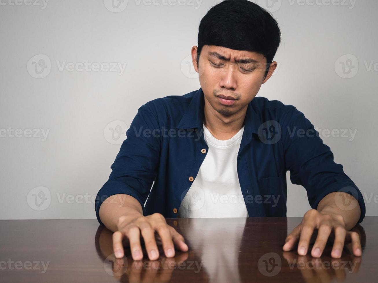 Der asiatische Mann, der am Tisch sitzt, fühlt sich deprimiert und traurig über das Leben foto