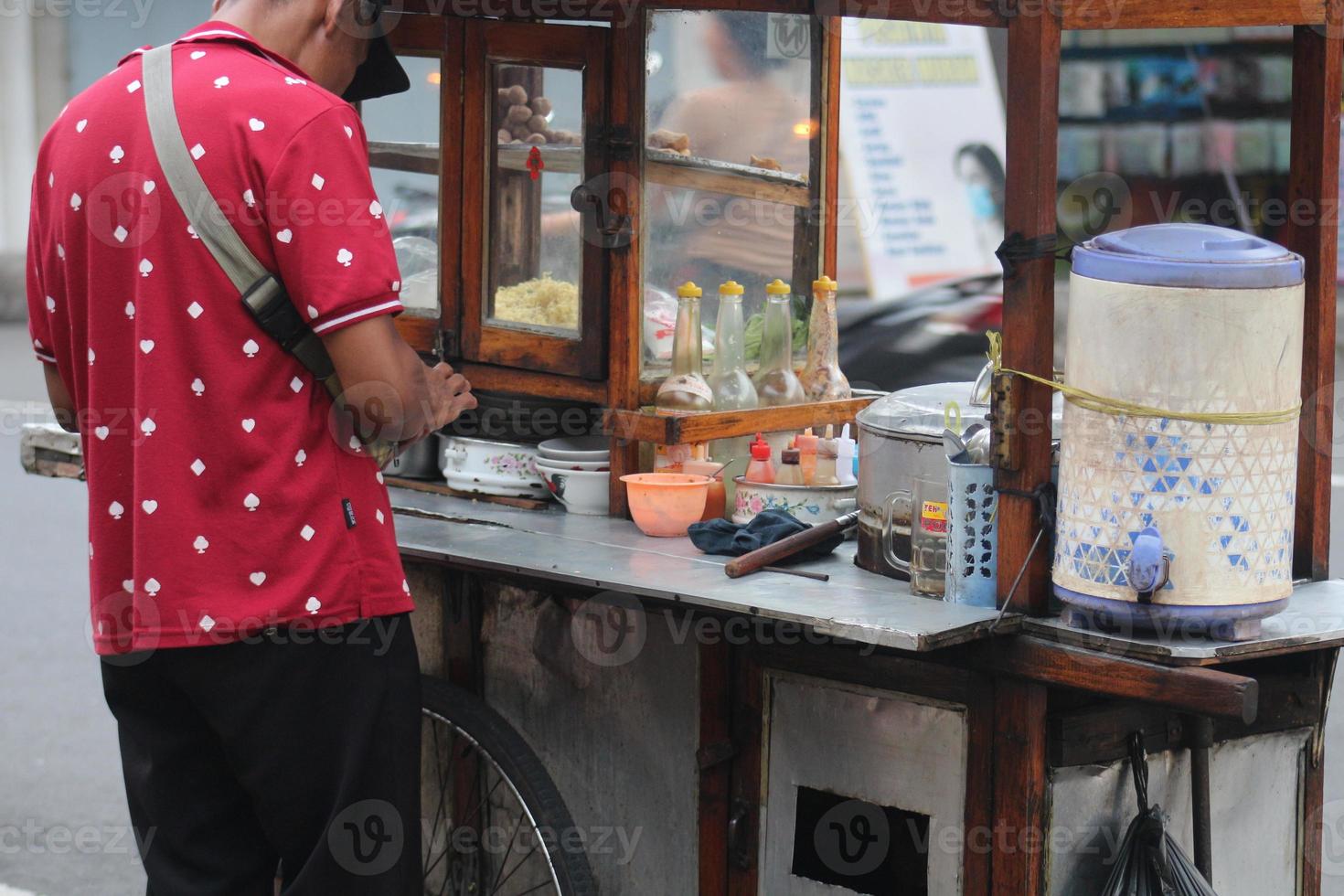 ein indonesischer penjual mie ayam bakso oder Verkäufer von Hähnchennudeln mit Fleischbällchen, der Hühnchennudeln für den Käufer herstellt. foto