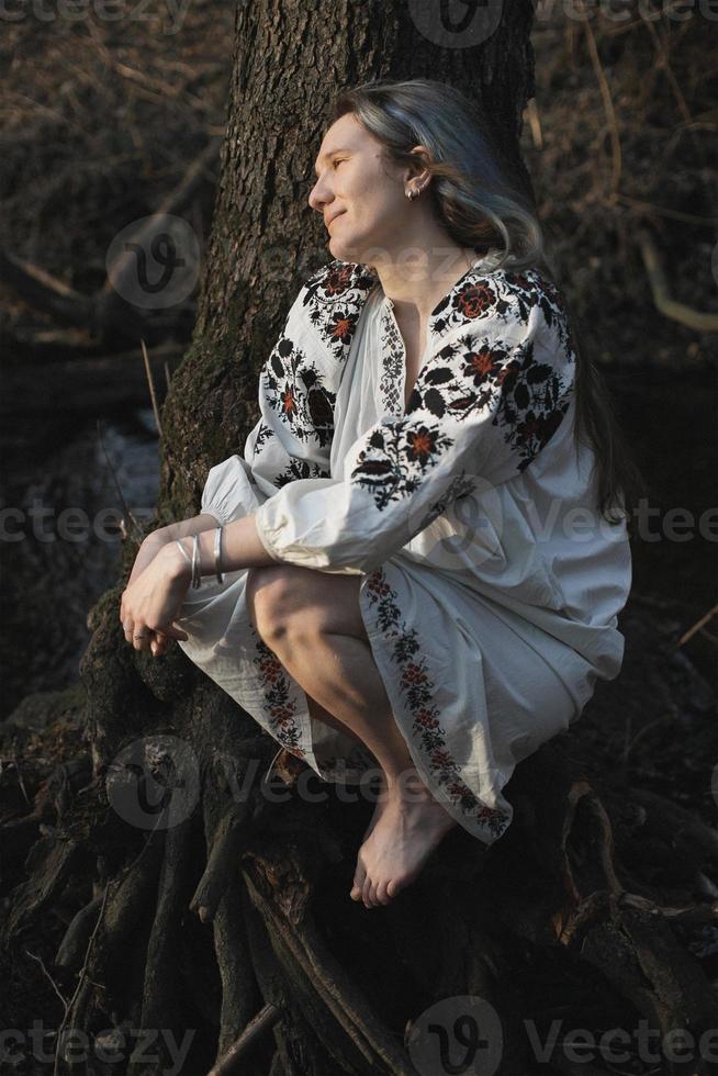 Nahaufnahme einer lächelnden Frau im ukrainischen Hemd, die ein stilles Waldporträtbild genießt foto