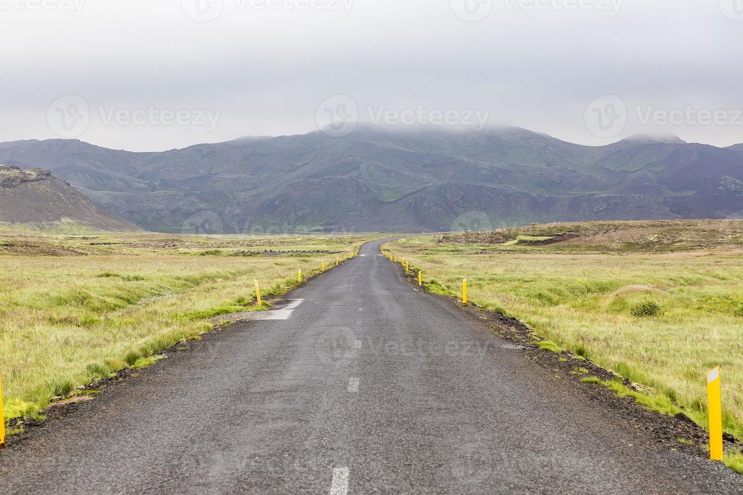 Gerade einsame Straße, die tagsüber Wiese auf Island überquert foto
