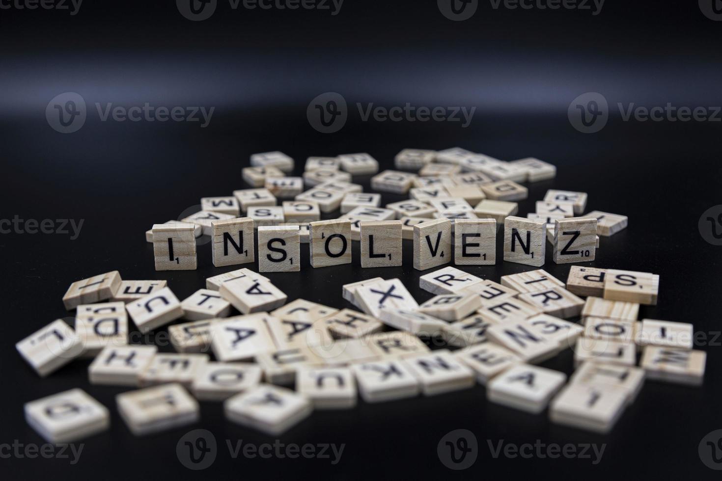 insolvenz - symbolische buchstaben - deutsche sprache - dunkler hintergrund foto