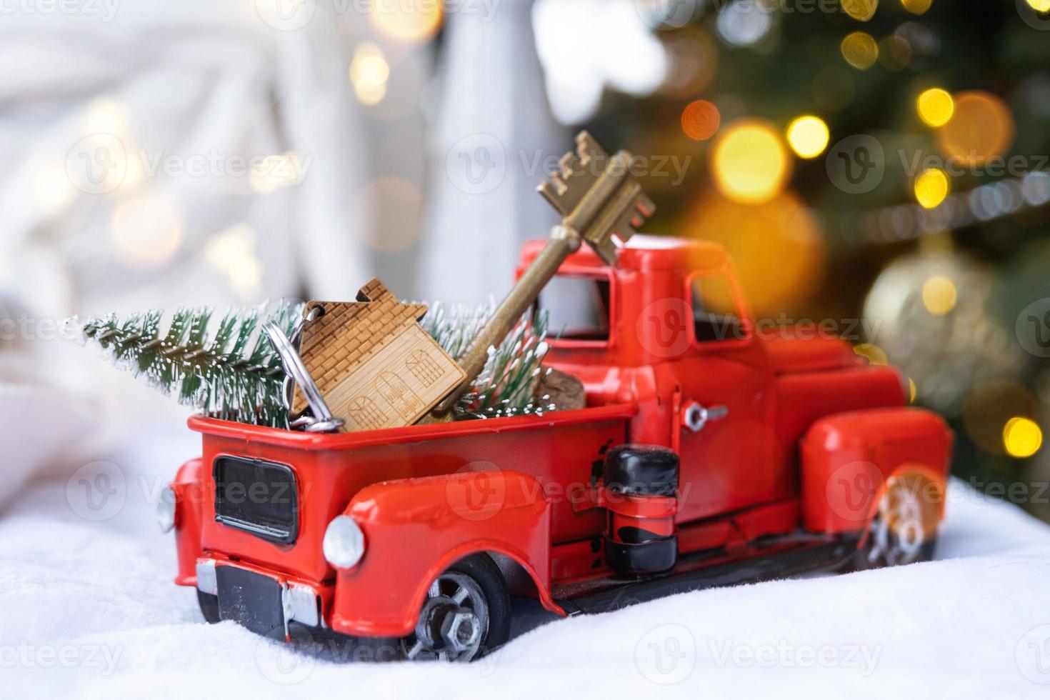 Rotes Retro-Auto mit einem Weihnachtsbaum schmückt mit dem Hausschlüssel im Pickup-Truck zu Weihnachten. Hauskauf, Umzug, Hypothek, Darlehen, Immobilien, Feststimmung, Neujahr foto