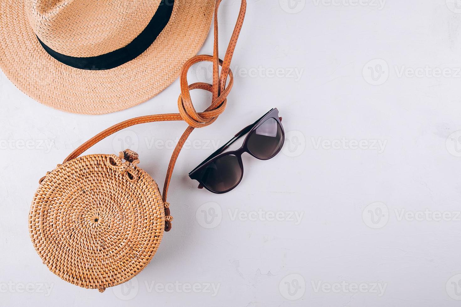 weibliches sommerreisemodekonzept. Strohsack, runde Rattantasche, Sonnenbrille auf weißem Hintergrund foto