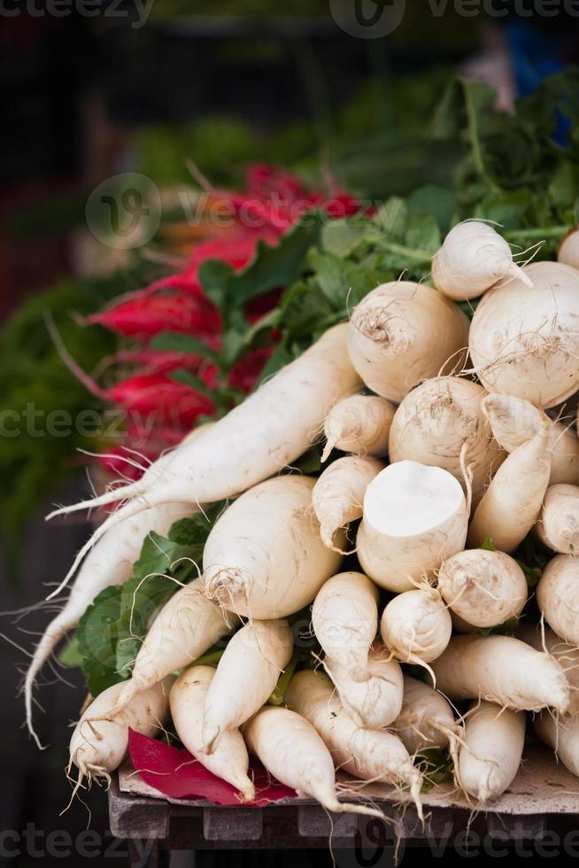 Weiße Radieschen stapeln sich auf einem Markt foto