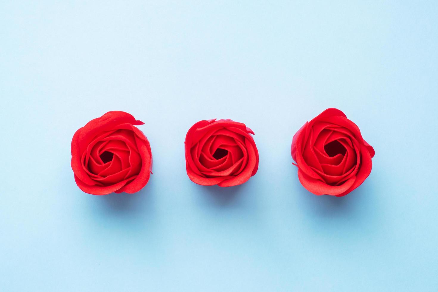 Handgemachte Seife in Form einer Rose, rote Rosenblüte auf blauem Hintergrund. draufsicht, minimalistisch, kopierraum. foto