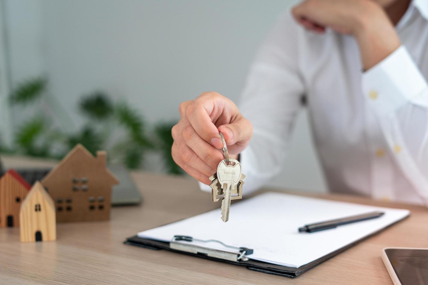 Der Makler oder Immobilienmakler sendet das Schlüsselhaus nach Abschluss des Bauprojekts an den Kunden. Haus kaufen, verkaufen oder mit einer Hypothek belasten, um ein Darlehen zu genehmigen. Hausratsversicherung foto