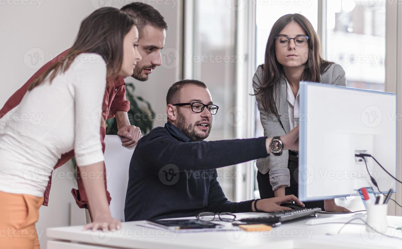 Multitasking-Geschäftsmann, der im Büro arbeitet. Er benutzt das Touchpad, während er eine E-Mail auf dem Laptop liest und sich Notizen auf dem Papier macht. foto