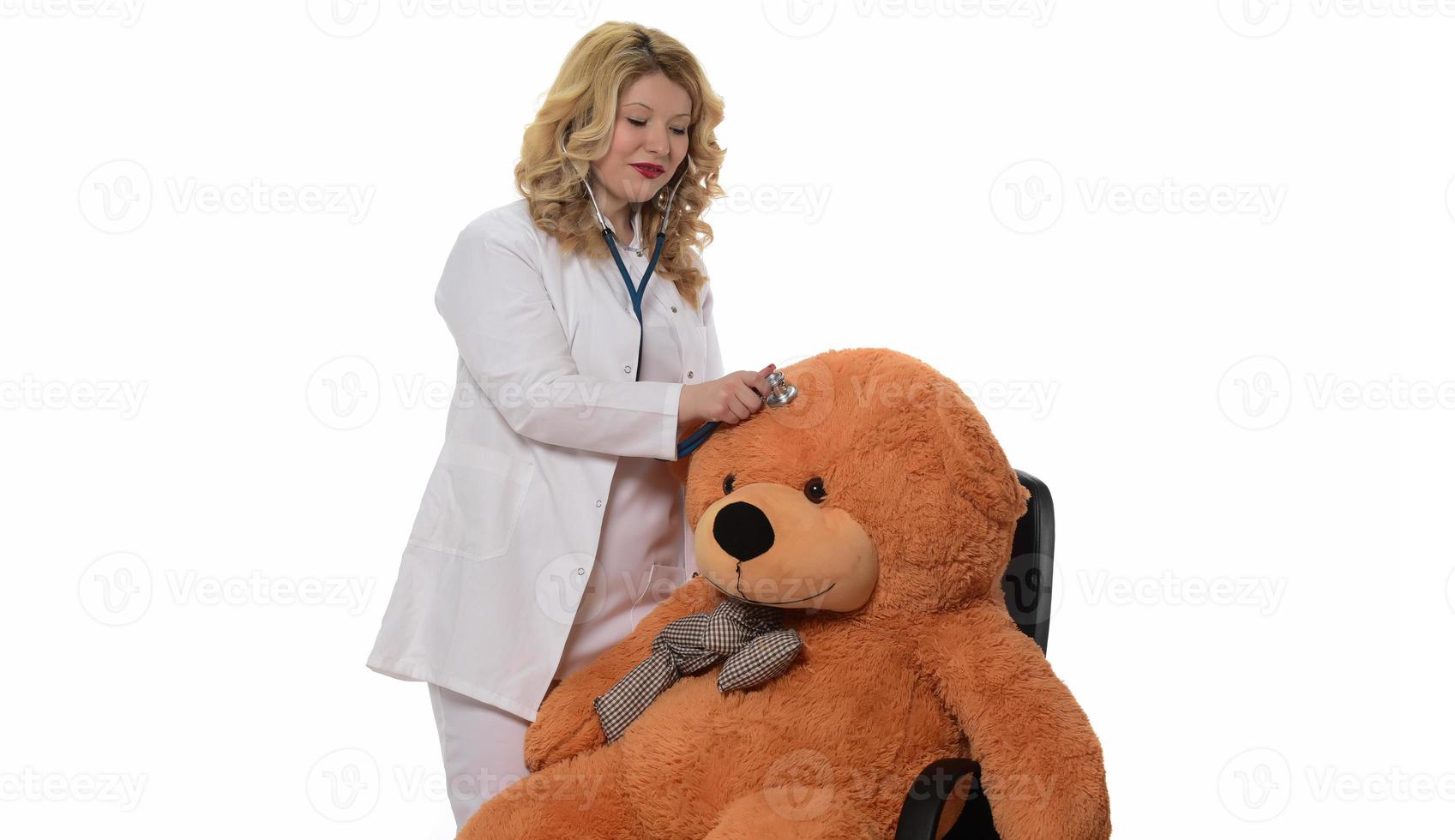 nahaufnahme einer jungen ärztin in uniform, die teddybär mit stethoskop in der klinik überprüft. Selbstbewusster Arzt oder medizinisches Fachpersonal, das den Teddybären im Krankenhaus untersucht foto