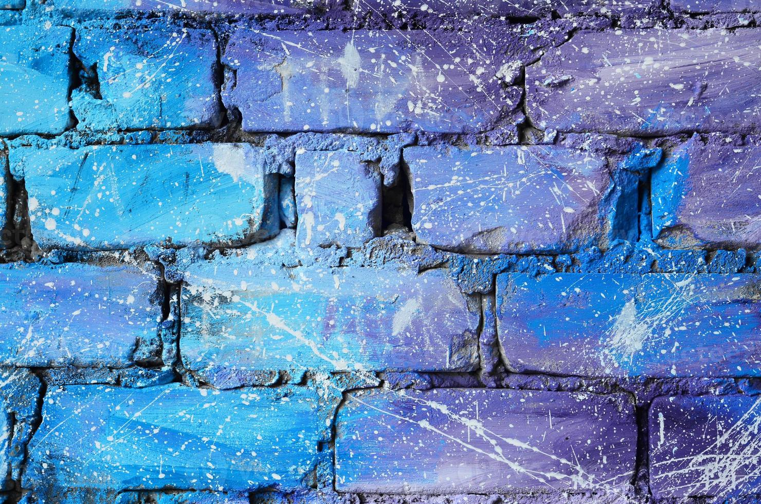 die Textur der alten Backsteinmauer, gemalt in blauen und violetten Farben mit achtlos verteilten weißen Tropfen und Spritzern, die die Sterne im Weltraum visualisieren foto