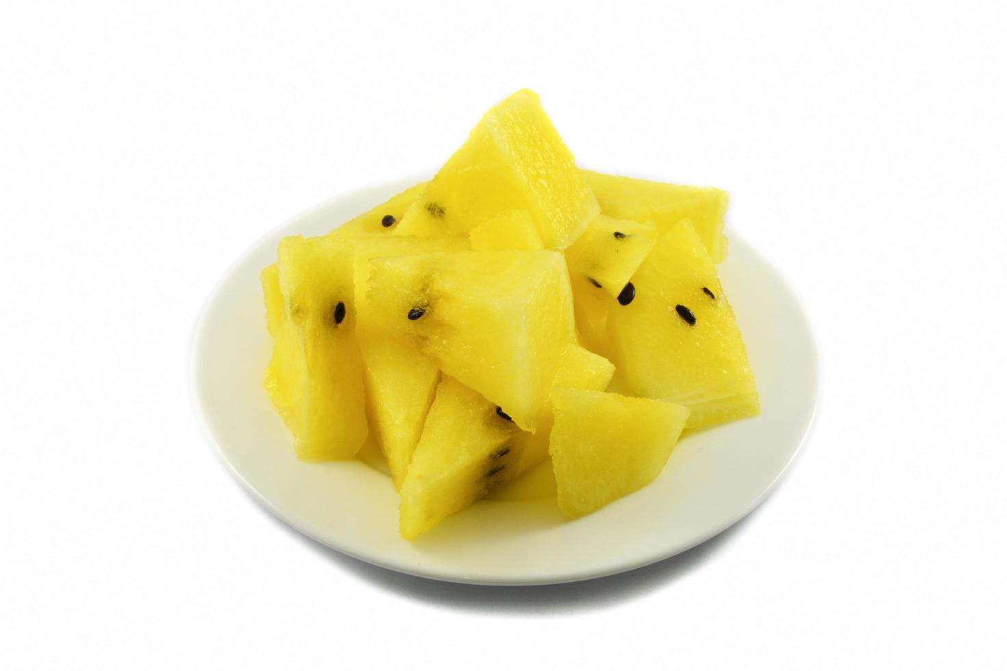 Gelbe Wassermelonenscheibe auf weißem Teller isoliert auf weißem Hintergrund foto