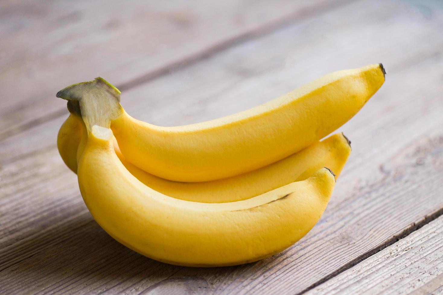 Bündel Bananen - Banane auf Holzhintergrund, reife Bananenfrucht auf dem Boden foto