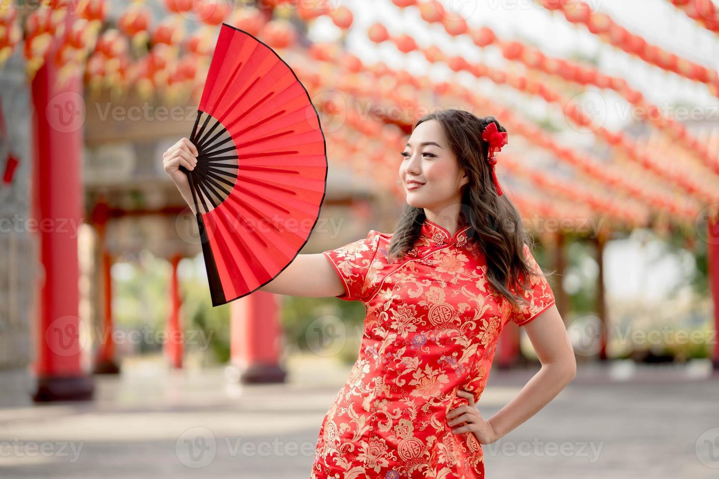 schöne dame, die traditionelles cheongsam qipao kostüm trägt, das fan im chinesischen buddhistischen tempel hält. Konzept des chinesischen Neujahrsfestes foto