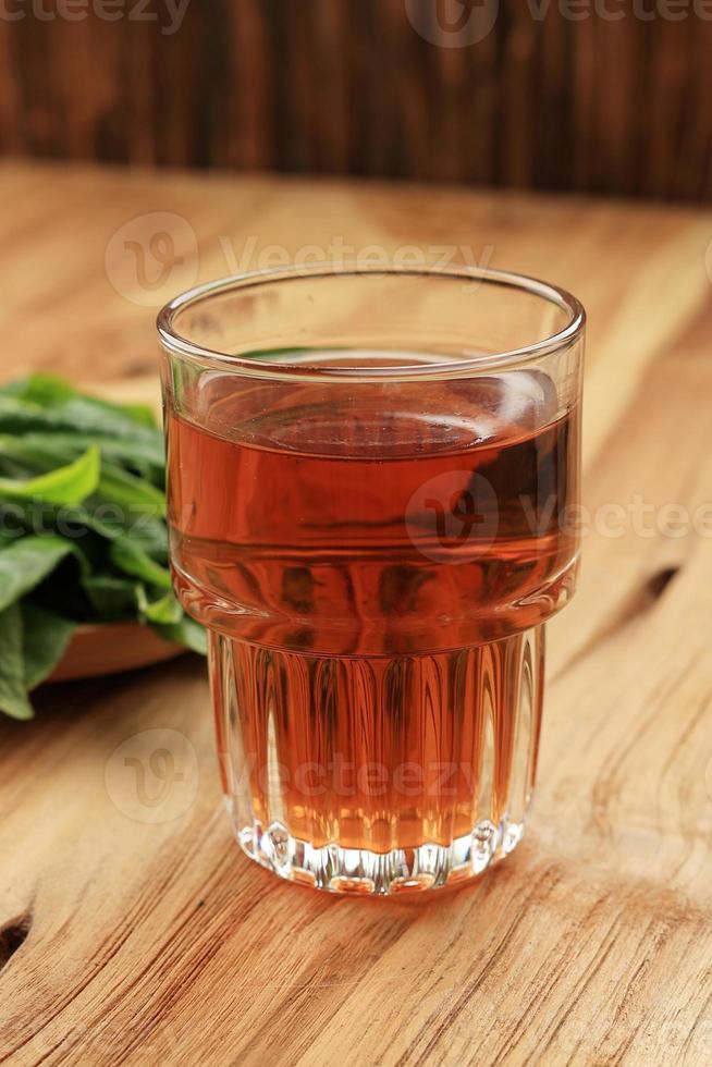 warmer tee in einem glas, mit frischem teeblatthintergrund foto
