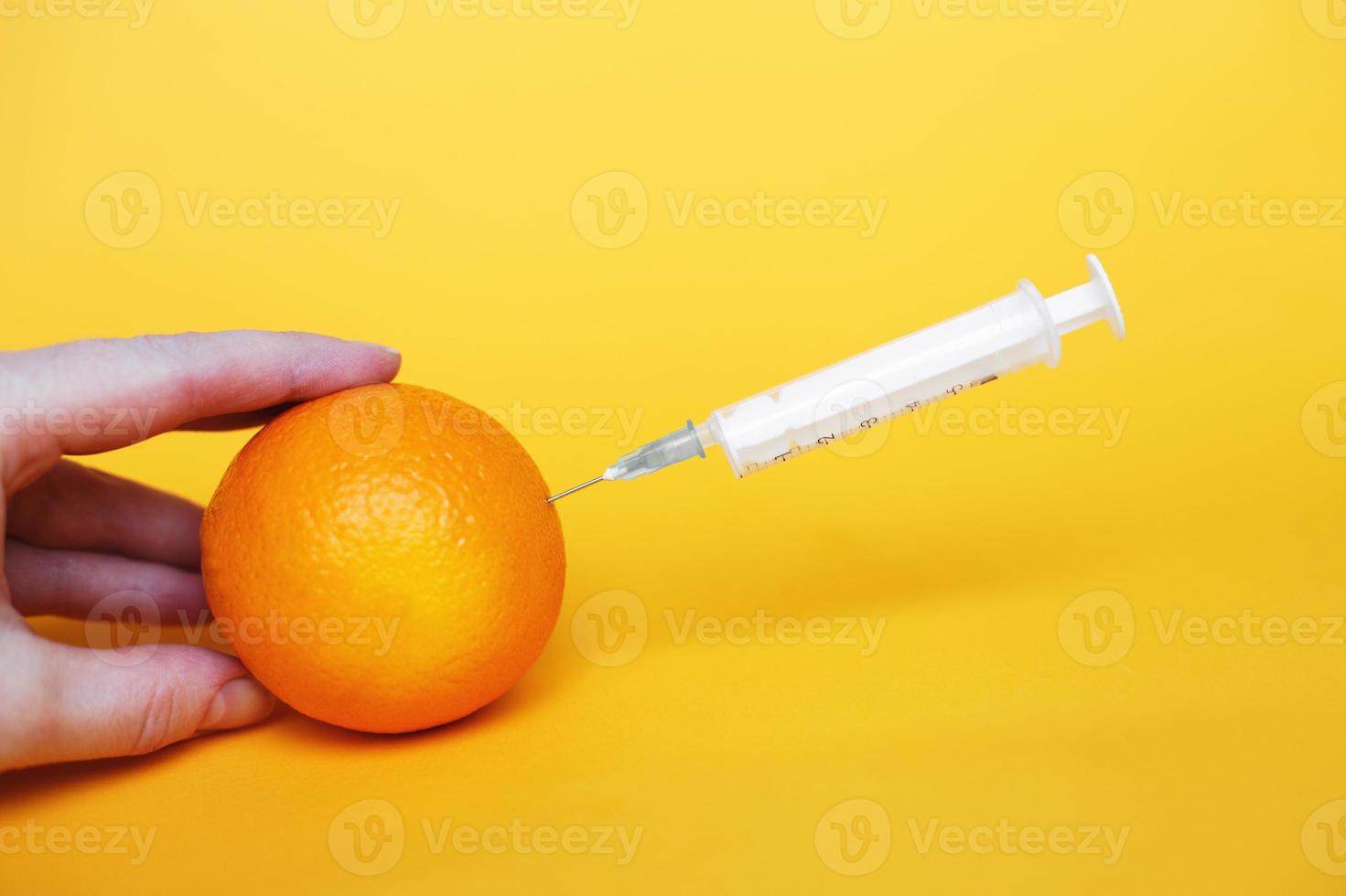Orangenfrüchte mit Spritze, die Flüssigkeit mit Vitamin C extrahiert. natürliches anti-aging-kosmetikkonzept foto