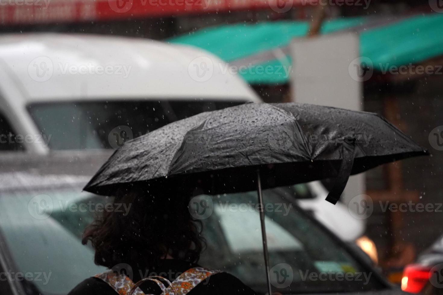 Öffnen Sie den schwarzen Regenschirm bei starkem Regen in Chinatown, New York City foto