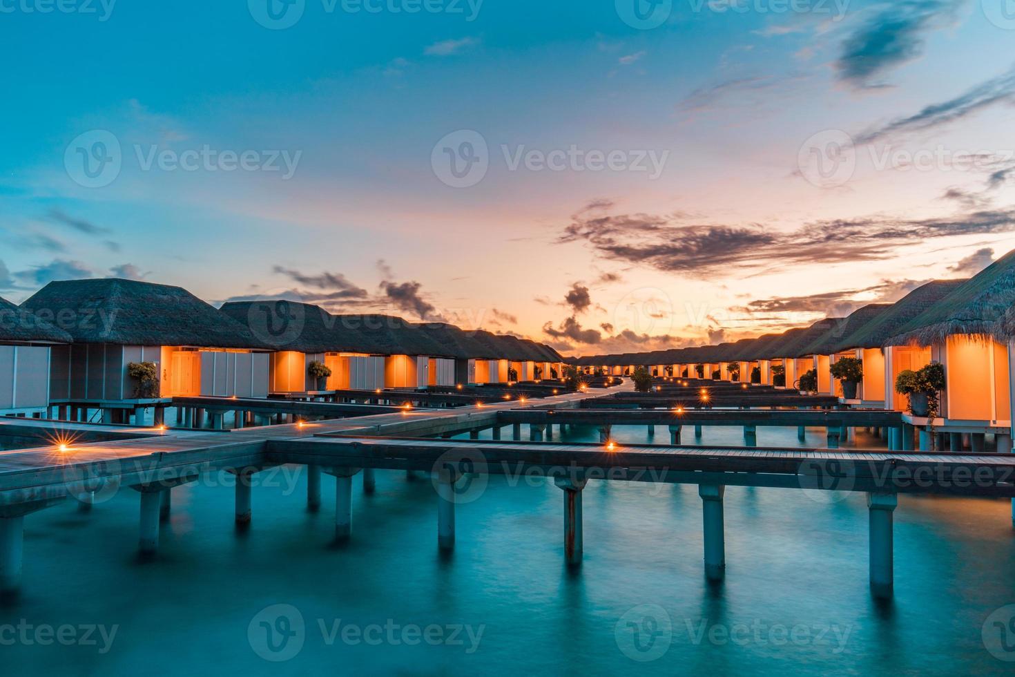 schöner himmel und meerwasser, luxuriöses tropisches resort, wasservillen mit lichtern bei sonnenuntergang. sommerinselhintergrund, luxuriöses urlaubsbanner. ruhige, entspannende Stimmung, inspirierende Naturlandschaft foto