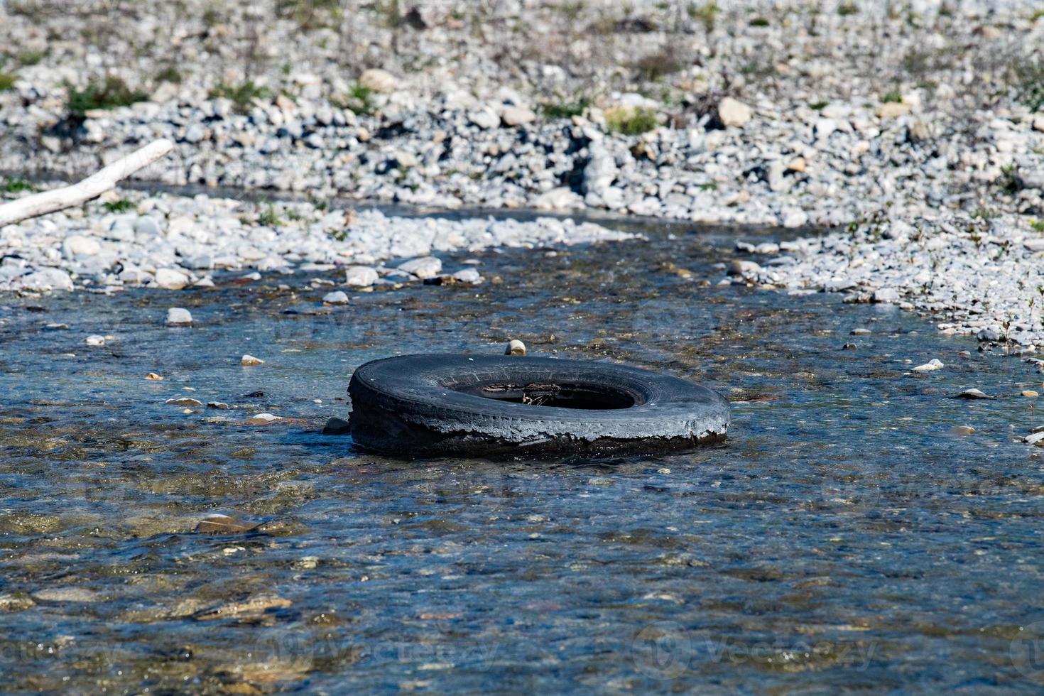 verlassener Reifen in einem Fluss foto
