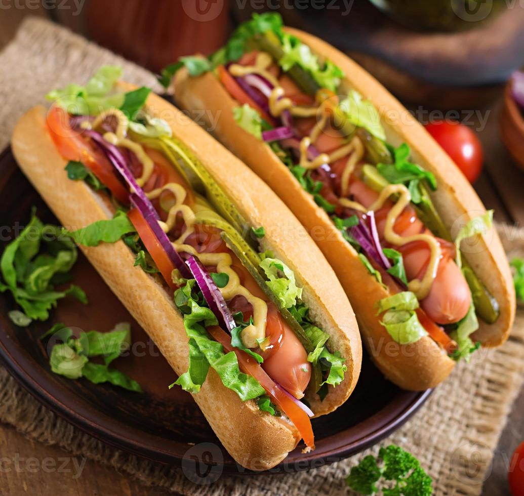 Hot Dog mit Gurken, Tomaten und Salat auf Holzhintergrund foto