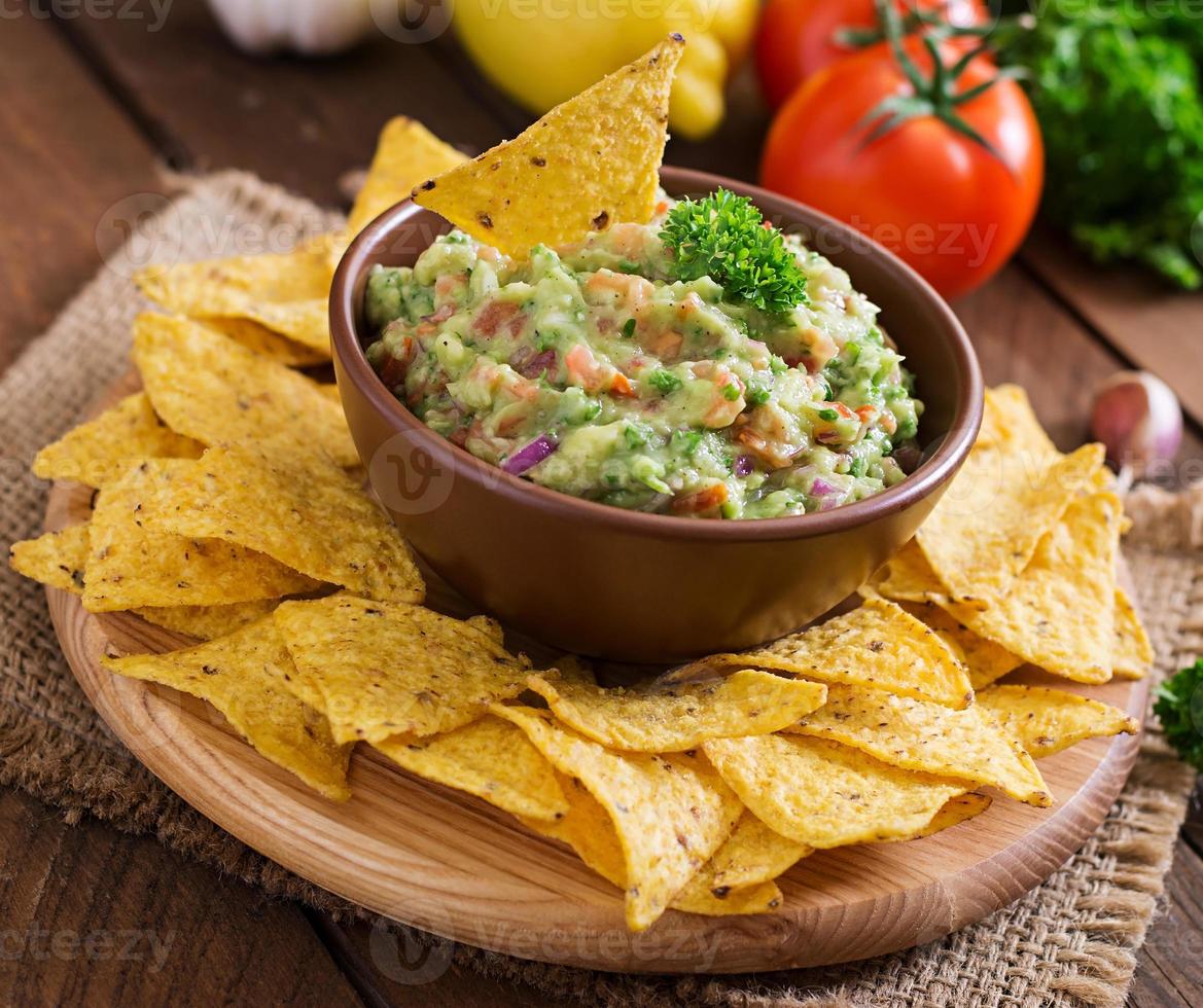 Guacamole Avocado, Limette, Tomate, Zwiebel und Koriander, serviert mit Nachos - traditioneller mexikanischer Snack foto