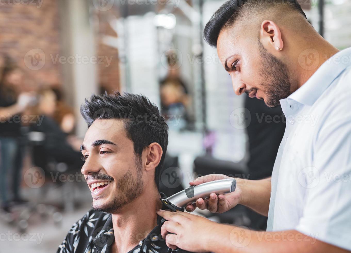 gutaussehender arabischer mann wird vom friseur im friseursalon rasiert foto