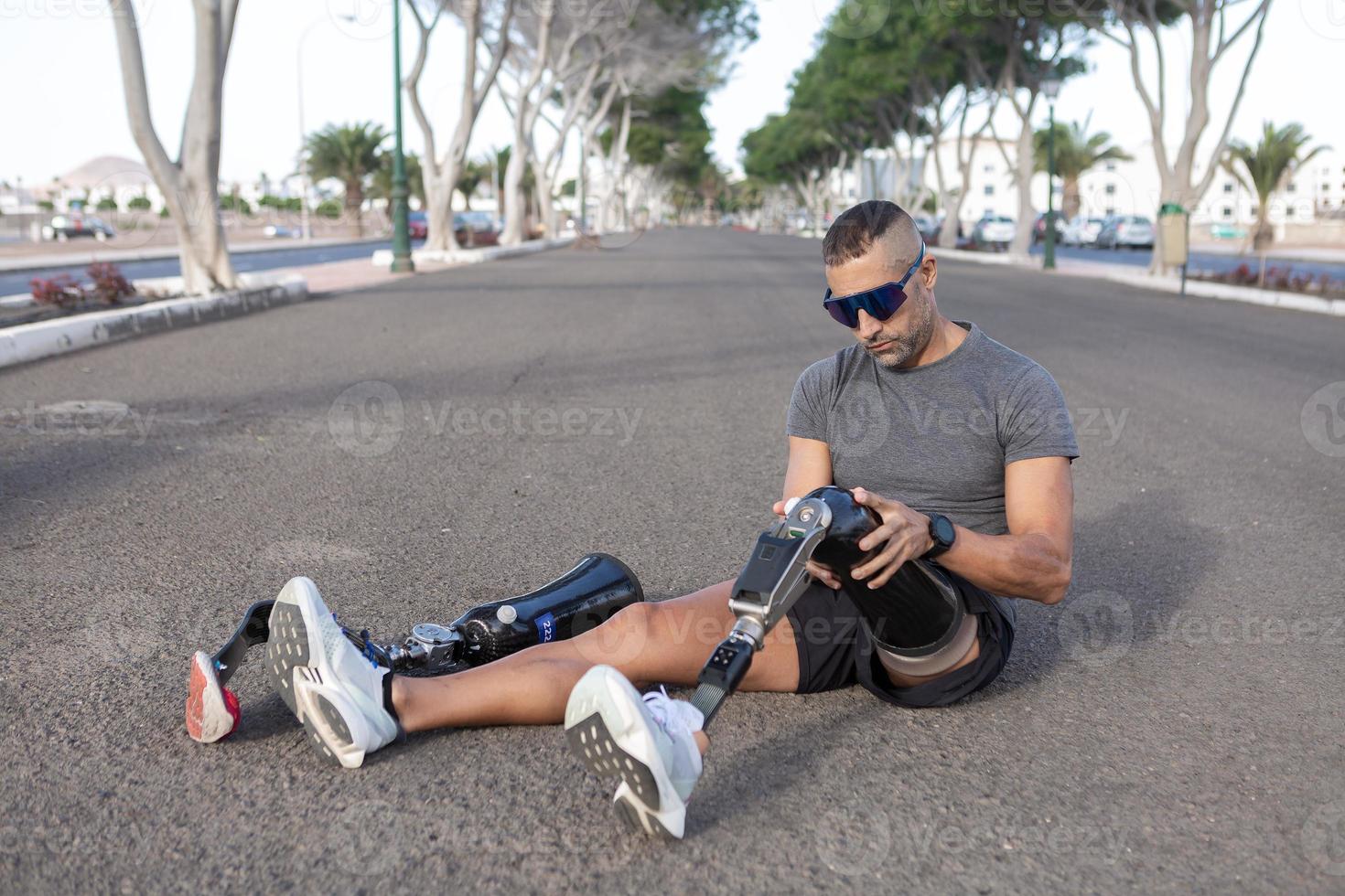 junger männlicher amputierter, der das künstliche bein zum laufen abnimmt foto