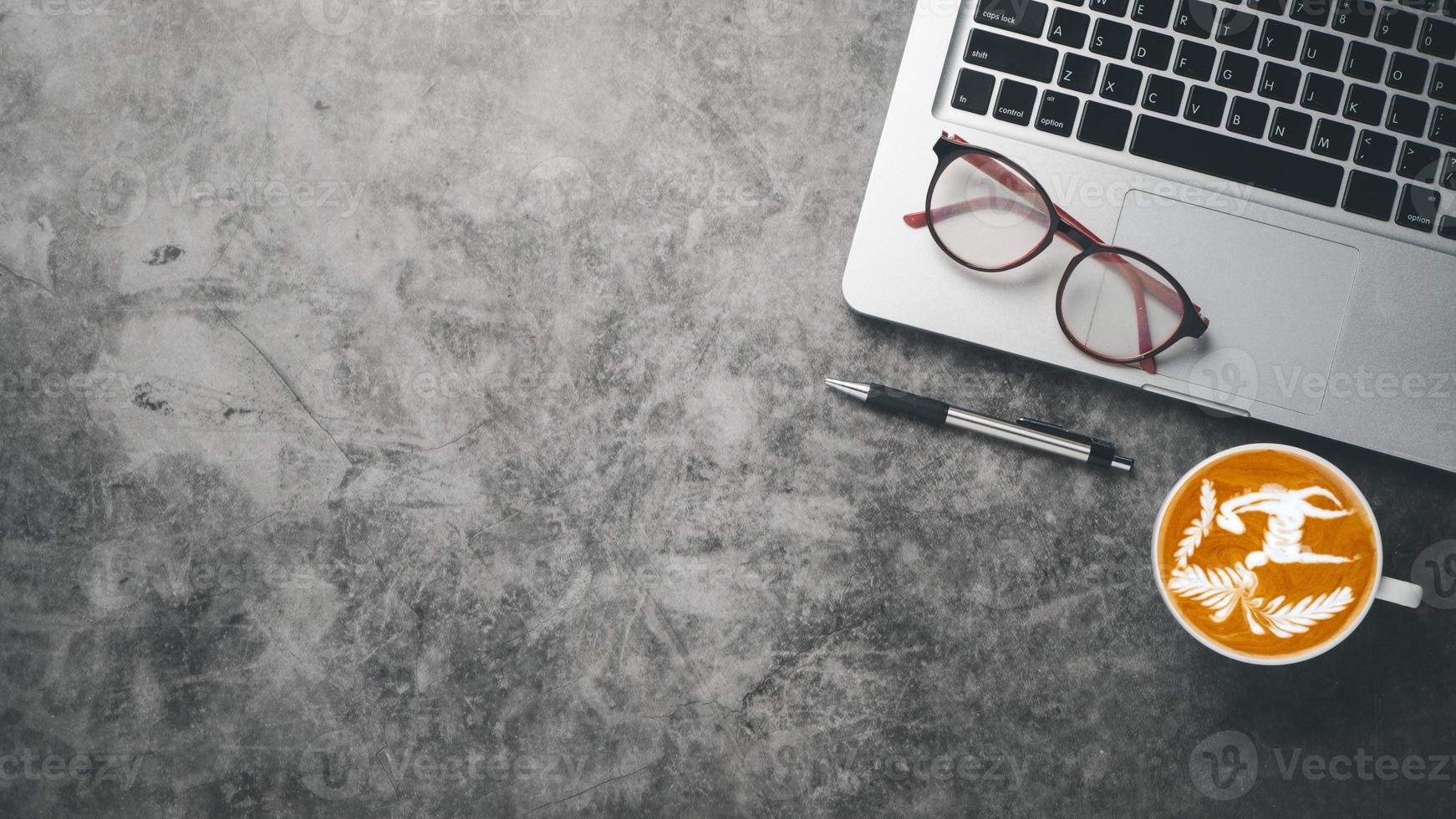 büroarbeitsplatz mit laptop-computer, brille, stift und tasse kaffee, draufsicht flach liegend mit kopierraum. foto