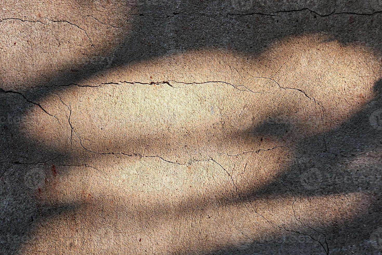 asphalthintergrund mit groben rissen. Sonnenlicht auf altem Beton. foto