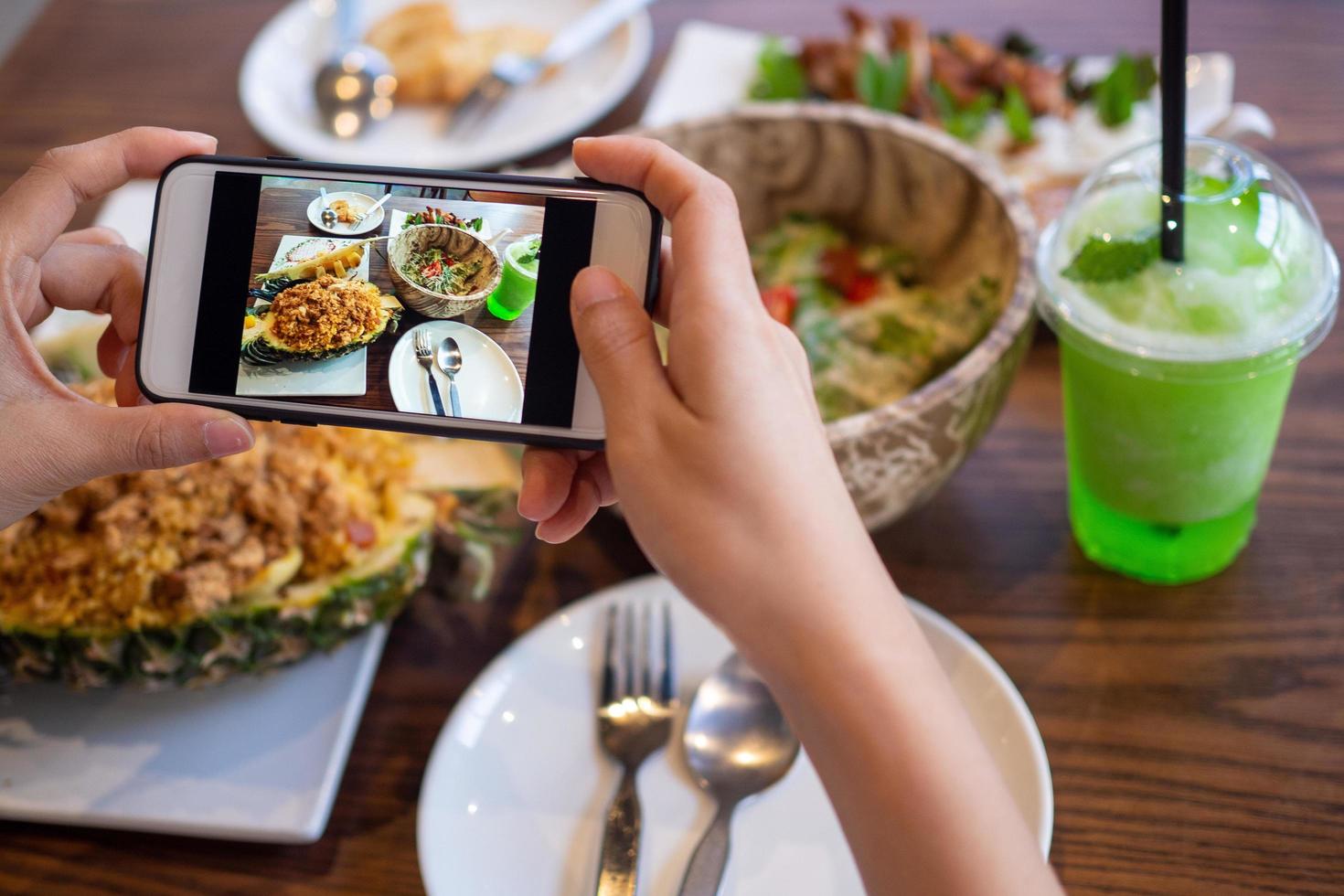 Die Hand einer Frau fotografiert von ihr selbst zubereitetes Essen. Lebensmittelverkäufer machen ein Foto mit einem Smartphone, um es auf der Website für die Online-Bestellung von Lebensmitteln zu veröffentlichen.