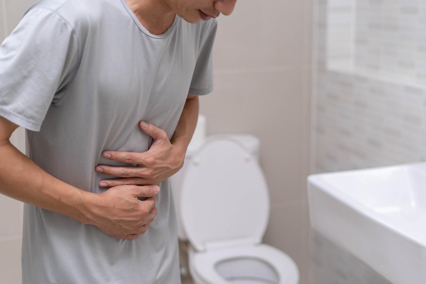 Durchfall, Bauchschmerzen, Verstopfungskonzept. Männer haben Wehen und Bauchschmerzen. Mann, der Toilettenpapier in der Toilette hält. foto