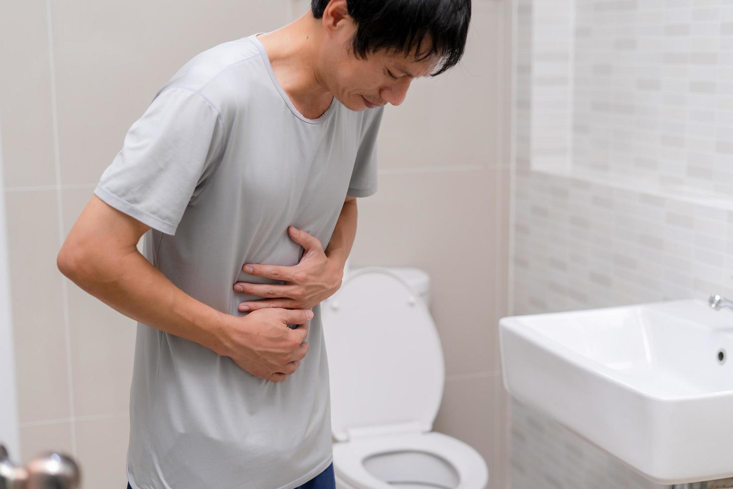 Durchfall, Bauchschmerzen, Verstopfungskonzept. Männer haben Wehen und Bauchschmerzen. Mann, der Toilettenpapier in der Toilette hält. foto