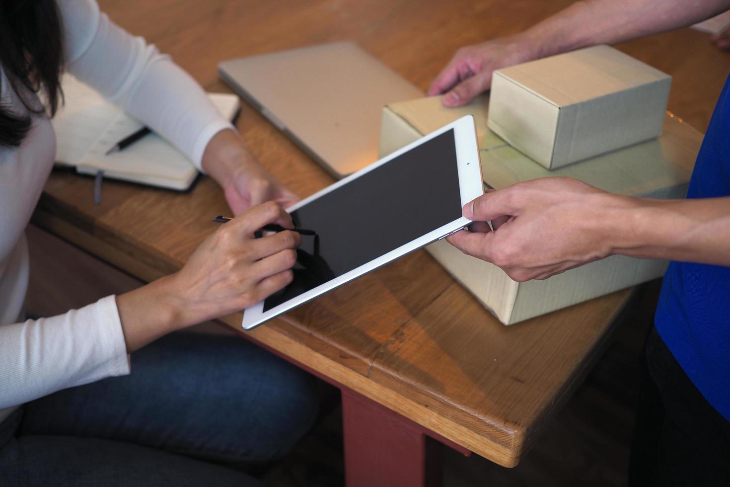 Das Käufermädchen unterschreibt auf dem Tablet, um die Paketbox vom Zusteller zu erhalten. schneller Lieferservice foto