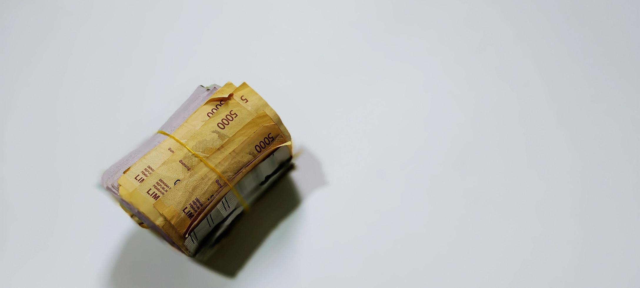 Gummirolle gefüllt mit indonesischen Banknoten verschiedener Konfessionen und Farben isoliert auf weißem Hintergrund foto