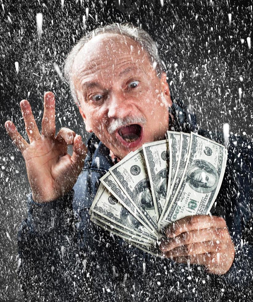 Mann mit einem Bündel Dollar im Schneefall foto