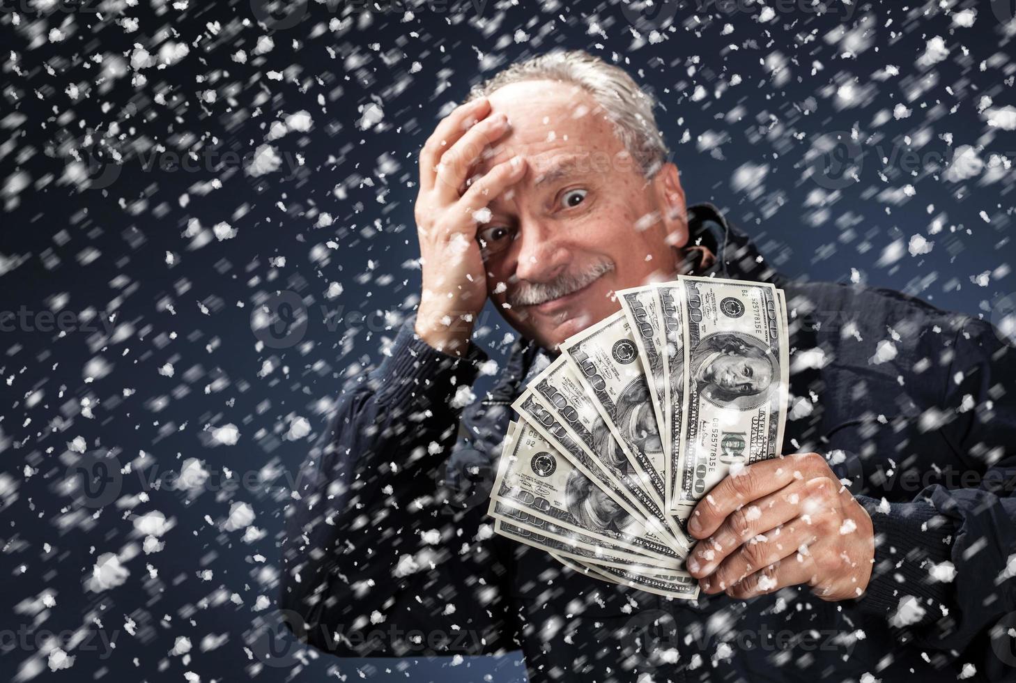 Mann mit einem Bündel Dollar im Schneefall foto