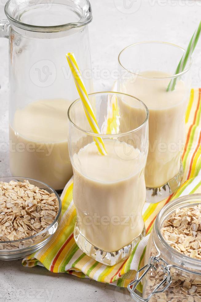 Dekanter und Gläser mit Hafermilch mit Trinkhalmen auf gelbgrünem Küchentuch. foto