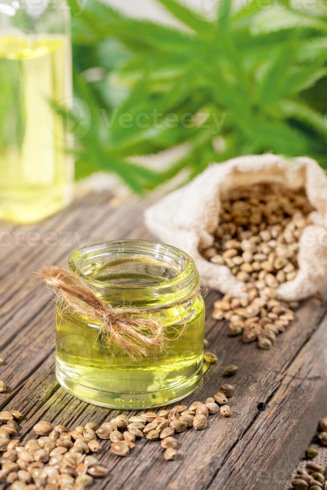 Hanfprodukte Öl im Glasgefäß im Vordergrund, Flasche, Cannabiskörner im Sack und Blätter im Hintergrund. foto