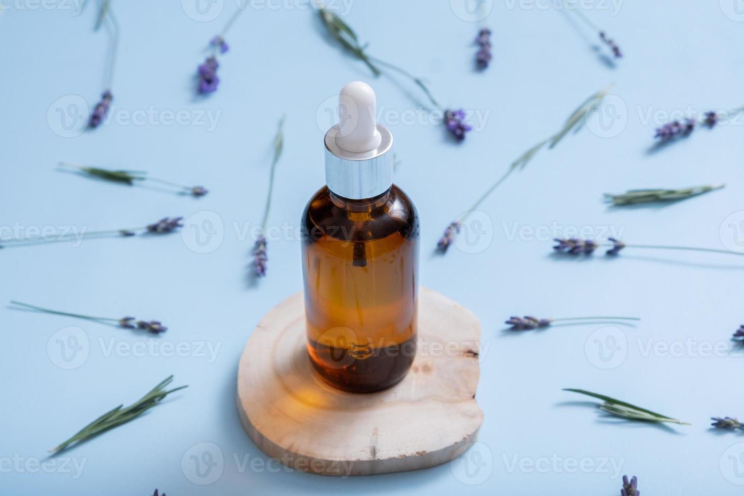 kosmetisches Öl in Pipettenflasche mit Lavendelblüten auf Draufsicht des farbigen Hintergrundes. Kräuterkosmetikkonzept foto