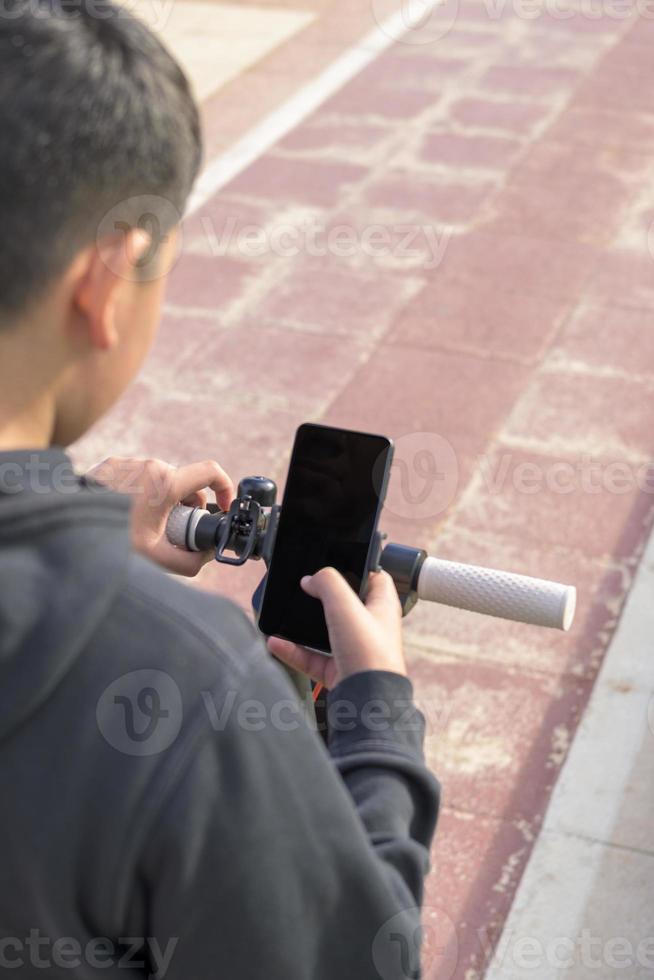 junger mann auf einem elektrischen skate mit smartphone-gps-anwendungen foto