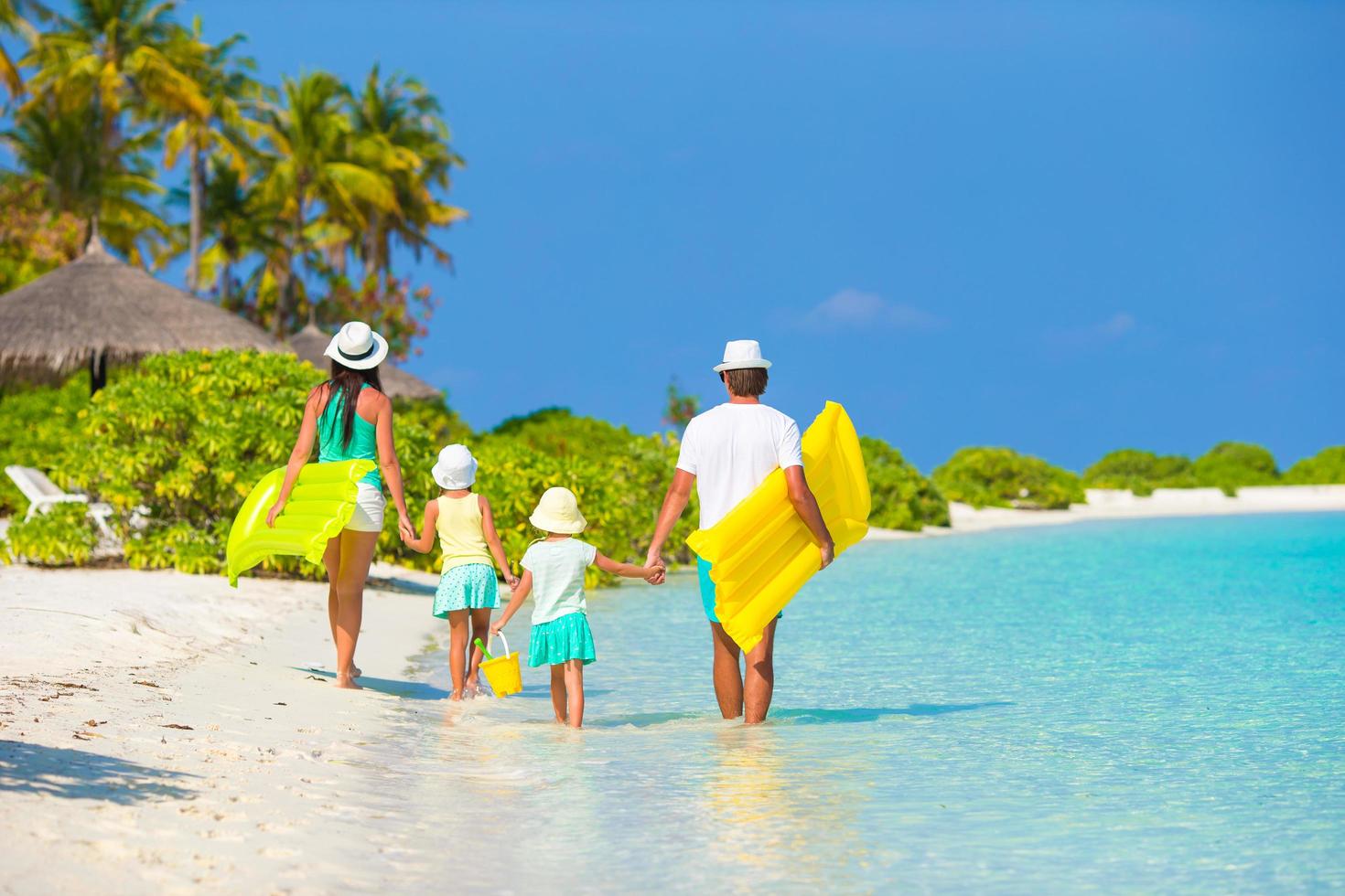 Familie spazieren mit Schwimmern am Strand foto