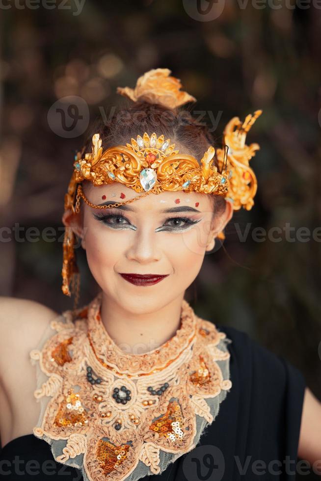 balinesische frau, die eine goldene krone und eine goldene halskette in ihrem make-up mit einem schönen gesicht trägt foto