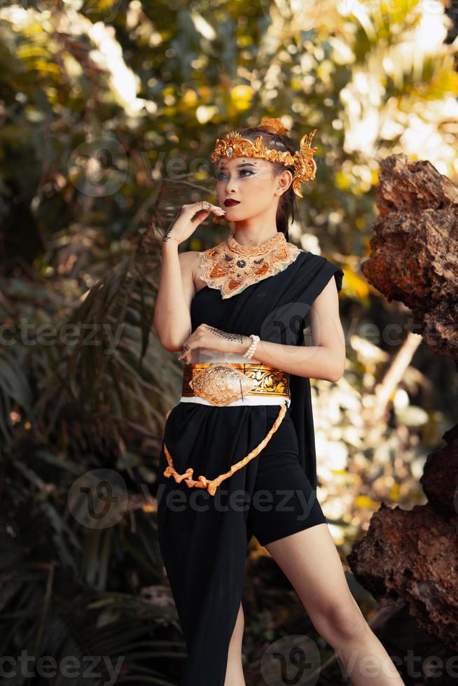 Schöne Stammesfrau, die eine goldene Königinkrone trägt, während sie ein schwarzes Kostüm trägt foto