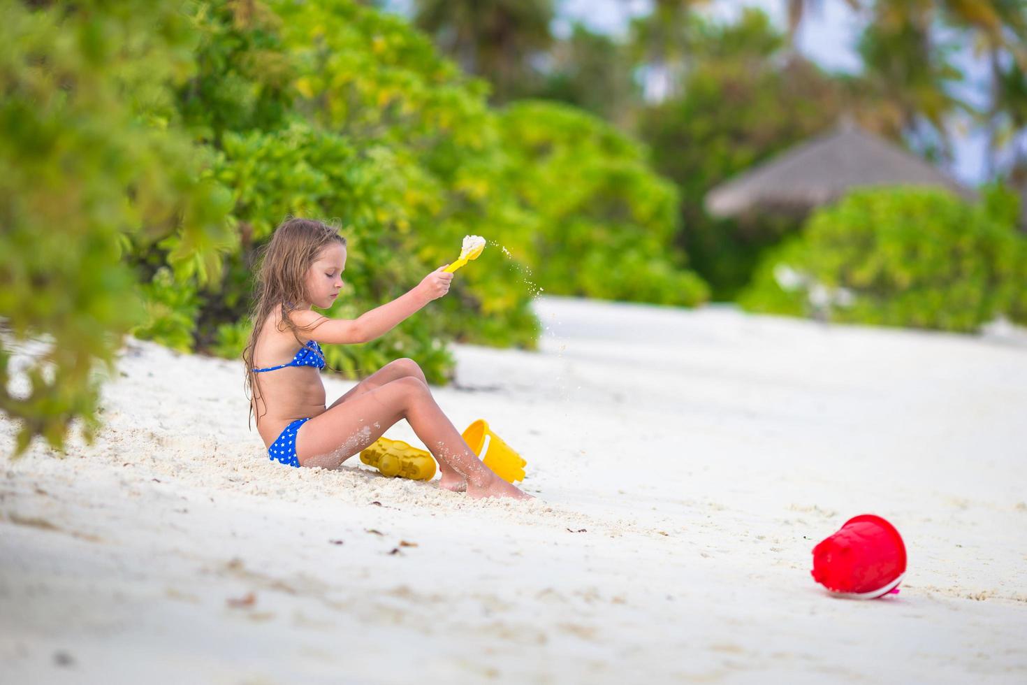 Mädchen, das Sand auf einem Strand schaufelt foto