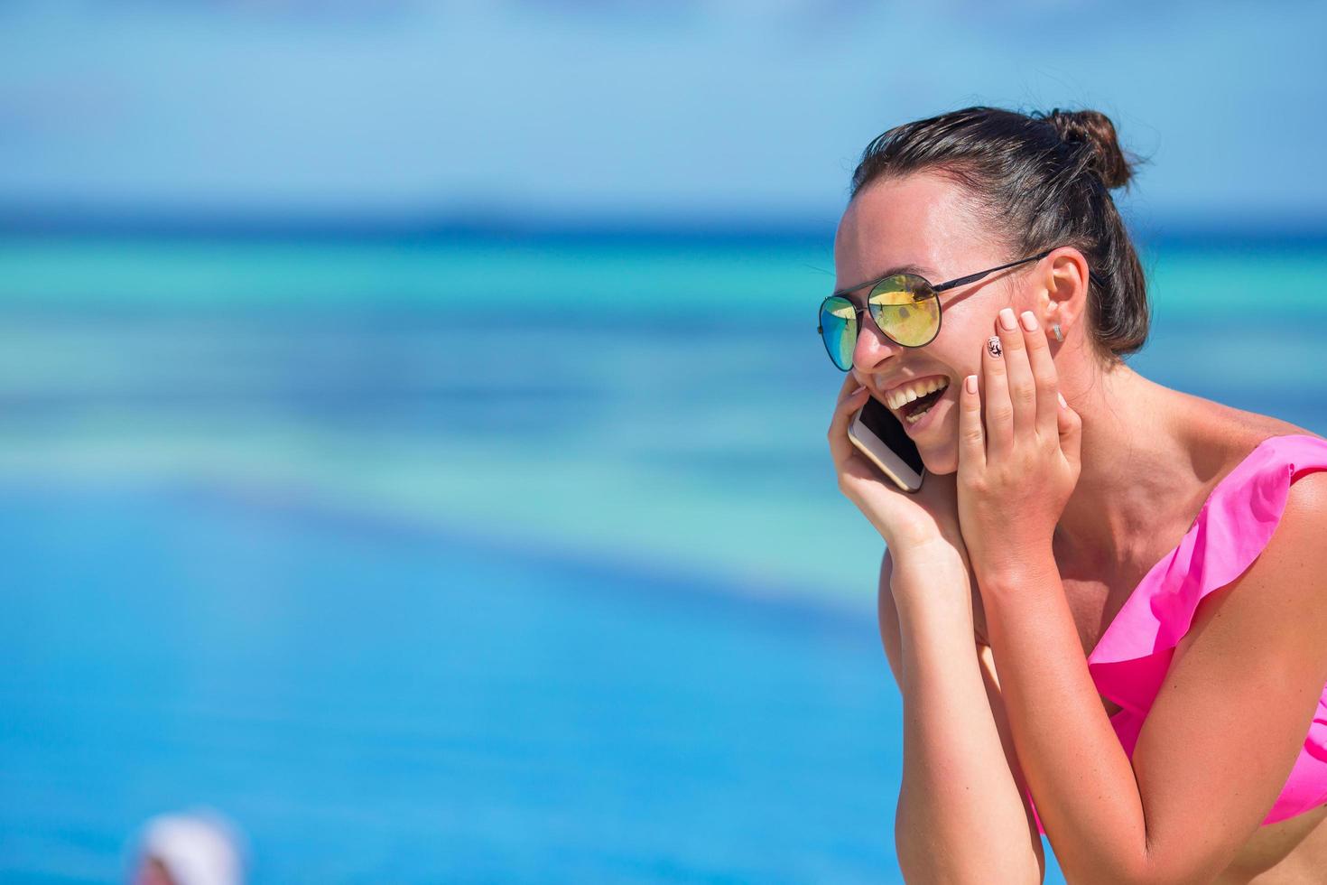 Frau, die am Strand am Telefon spricht foto