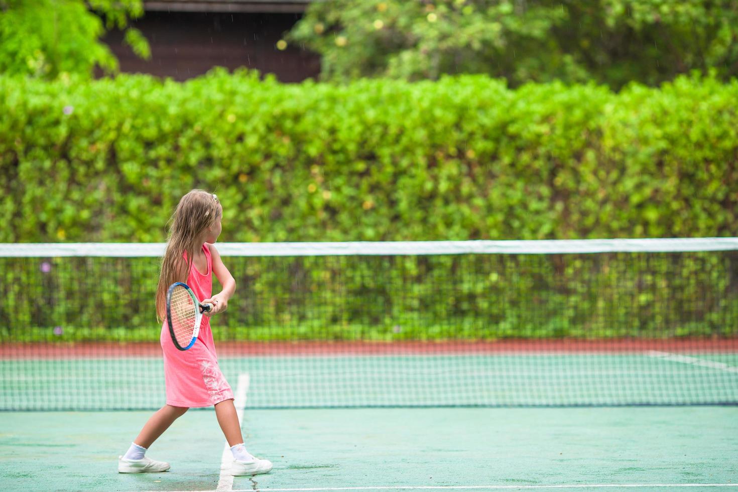 Mädchen, das Tennis im rosa Kleid spielt foto