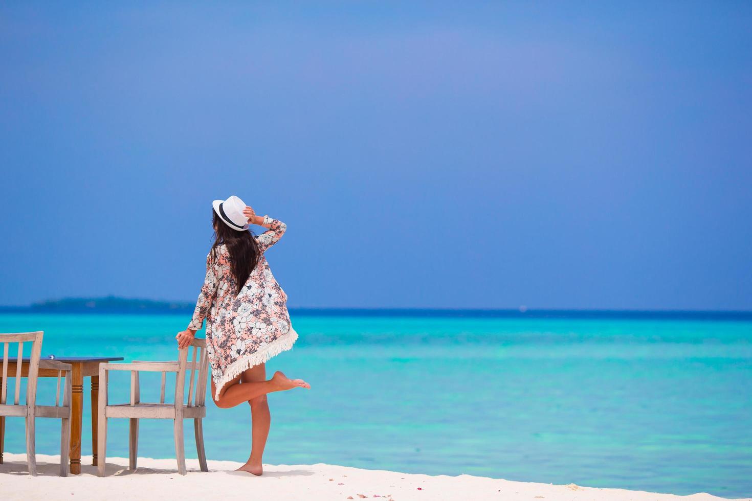 Frau posiert mit einem Stuhl am Strand foto